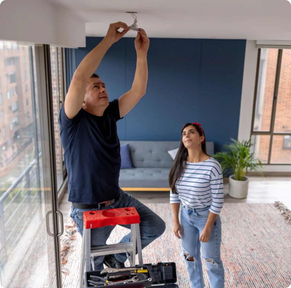 Man fixing ceiling light with woman's help